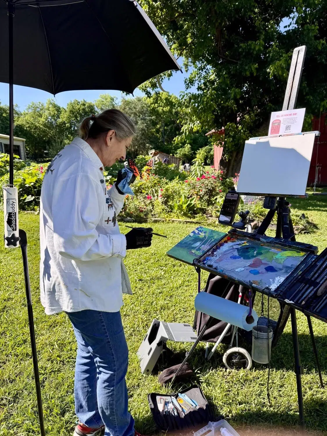 Artist painting outdoors under an umbrella on the Four Winds grounds in Bonham Texas